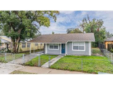 Gray house with blue door, walkway, and grassy yard at 3409 E Comanche Ave, Tampa, FL 33610