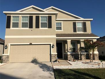 Two-story house with beige exterior, stone accents, and a three-car garage at 10913 Kidron Valley Ln, Tampa, FL 33625