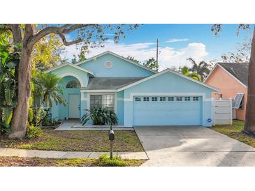 Light blue house with a two-car garage and well-maintained lawn at 14721 Condor Pass, Clearwater, FL 33760