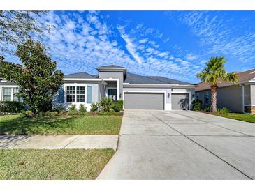 Two-story home with gray siding, three-car garage, and landscaped front yard at 17721 Bright Wheat Dr, Lithia, FL 33547