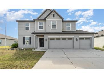 Two-story house with gray siding, three-car garage, and landscaping at 2436 Sand Gables Trl, Bradenton, FL 34208