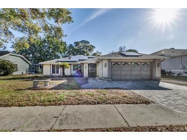 Single-story home with a gray roof, solar panels, and a paved driveway at 3028 Summervale Dr, Holiday, FL 34691