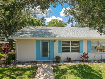 Tan house with blue shutters, walkway, and landscaping at 402 Dorchester Pl # 28, Sun City Center, FL 33573