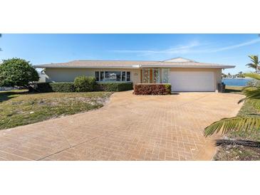 Tan single-story home with a large driveway and mature landscaping at 495 Bath Club N Blvd, North Redington Beach, FL 33708