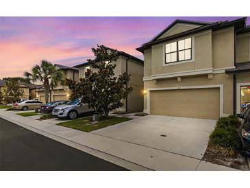 Tan three-story townhome with two-car garage, at dusk at 5152 Bay Isle Cir, Clearwater, FL 33760