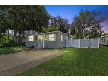 Gray house with a stone base, white fence, and well-maintained lawn at 6108 Pershing Ne St, St Petersburg, FL 33703