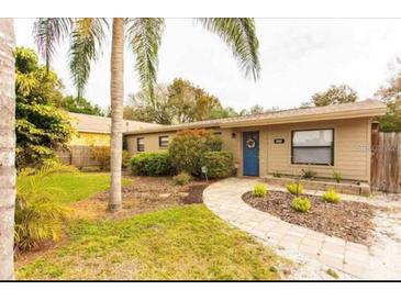 Charming single-story home with blue front door, landscaped yard, and brick walkway at 10405 N Woodmere Rd, Tampa, FL 33617