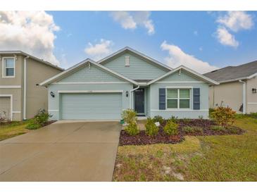 One-story home with light blue siding, a two-car garage, and a well-maintained lawn at 11520 Koti Creek Ln, Thonotosassa, FL 33592