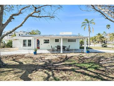 Front view of a charming ranch home with a covered patio and landscaped yard at 17602 Sterling Ter, Redington Shores, FL 33708