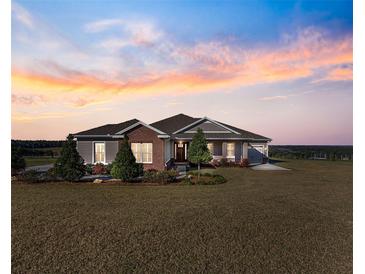 Brick and siding one-story home with landscaped yard at sunset at 36511 Frazee Hill Rd, Dade City, FL 33523