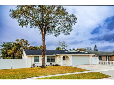 Newly renovated house with a white exterior, landscaped lawn, and attached garage at 7097 Aberfeldy N Ave, St Petersburg, FL 33709