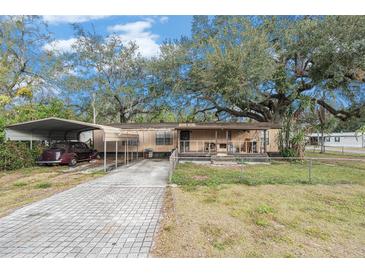 Mobile home with carport, paved driveway, and large shade trees at 7401 Mount Vernon Rd, Tampa, FL 33625