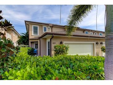 Tan two-story house with attached garage, landscaping, and a hedge in front at 820 Date Palm Ln, St Petersburg, FL 33707