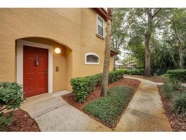 Inviting condo exterior featuring a red door and well-manicured landscaping at 2254 Chianti Pl # 68, Palm Harbor, FL 34683