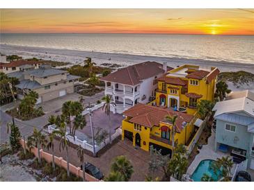 Beachfront property with a luxurious yellow house and a stunning sunset view at 3702 El Centro St, St Pete Beach, FL 33706