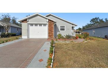 Gray house with brick accents, attached garage, and landscaped front yard at 37401 Wedgewood Dr, Zephyrhills, FL 33542