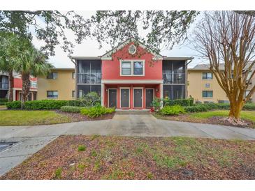 Two-story condo building with red exterior, screened patios, and landscaping at 5557 Baywater Dr, Tampa, FL 33615