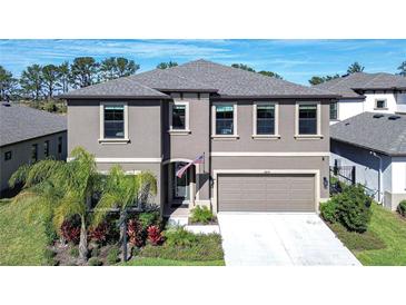 Two-story house with gray siding, a three-car garage, and palm trees at 14834 Paddock Pond Ave, Lithia, FL 33547