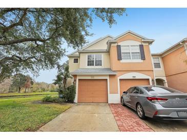 Two-story townhome with attached garage and brick driveway, located by a pond at 2552 Glenrise Pl, Wesley Chapel, FL 33544