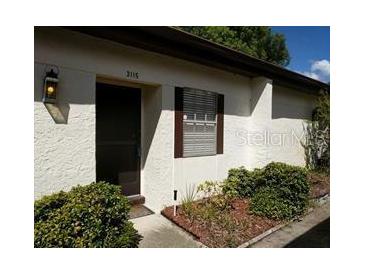 Exterior view of a condo building with a well-maintained front entrance and landscaping at 3115 Mission Grove Dr, Palm Harbor, FL 34684