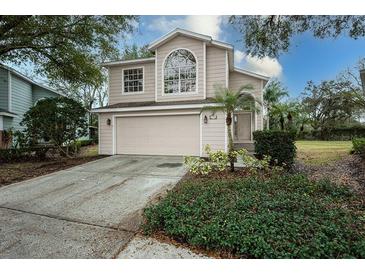 Two-story house with beige siding, attached garage, and landscaping at 5147 Sterling Manor Dr, Tampa, FL 33647