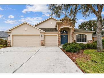 House exterior featuring a three-car garage and stone accents at 6944 Runner Oak Dr, Wesley Chapel, FL 33545