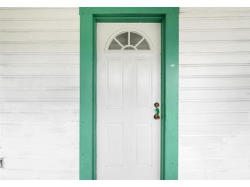 White front door with a green frame and arched window at 710 Seminole St, Clearwater, FL 33755