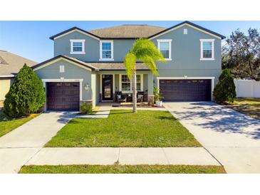 Two-story house with a green exterior, two-car garage, and palm tree at 13458 Graham Yarden Dr, Riverview, FL 33579