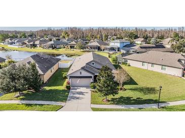 Aerial view of a single-Gathering home with a landscaped yard and a lake in the background at 19724 Post Island Loop, Land O Lakes, FL 34638