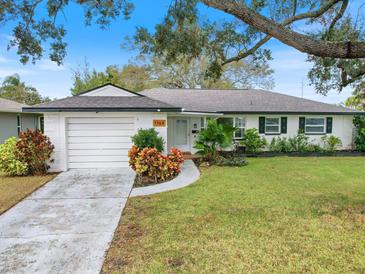 White house with green lawn, driveway, and mature trees at 1768 Algonquin Dr, Clearwater, FL 33755