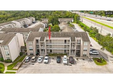 Exterior view of condo building with parking lot and nearby highway at 2625 State Road 590 # 532, Clearwater, FL 33759