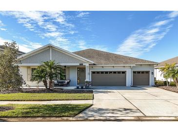 Two-story house with gray siding, three-car garage, and landscaped lawn at 7853 Roma Dune Dr, Wesley Chapel, FL 33545