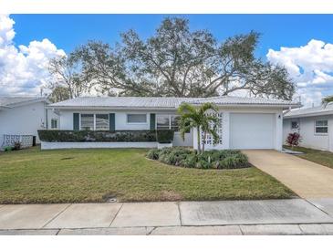 White single-story home with green shutters, a large tree, and a well-manicured lawn at 4526 101St N Ave, Pinellas Park, FL 33782