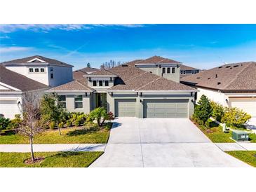 Two-story house with a three-car garage and landscaped front yard at 5612 Limelight Dr, Apollo Beach, FL 33572