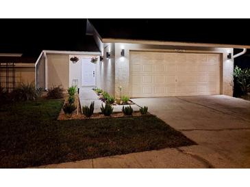 Well-lit home exterior at night, showcasing landscaping and a garage at 10820 Livingston Dr, New Port Richey, FL 34654