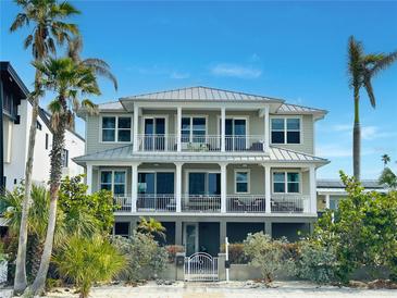 Beautiful two-story home with a gray exterior, white trim, and a metal roof at 1205 Gulf Way, St Pete Beach, FL 33706