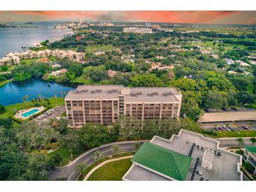 Stunning aerial view of the condo building, pool, and surrounding landscape with water views at 220 Belleview Blvd # 811, Belleair, FL 33756