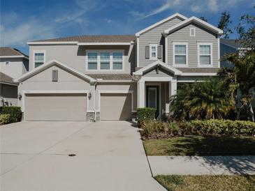 Two-story house with gray siding, three-car garage, and landscaped yard at 5709 Camila Song Ln, Tampa, FL 33625