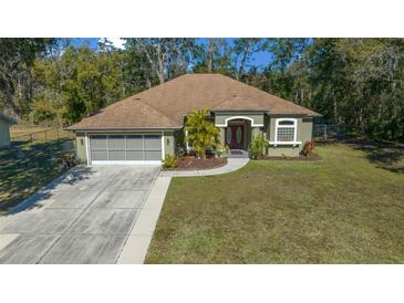Single-story house with a two car garage and a well maintained lawn at 628 Erin Way, Brooksville, FL 34601