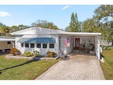 White single-wide manufactured home with covered carport and landscaped yard at 9790 66Th N St # 130, Pinellas Park, FL 33782