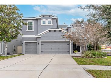 Two-story house with gray siding, two-car garage, and landscaping at 10409 Waterstone Dr, Riverview, FL 33578
