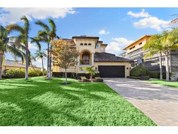 Two-story house with a tan facade, a large garage door, and a nicely landscaped lawn at 110 Driftwood Ln, Largo, FL 33770