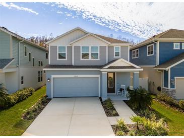 Two-story house with light blue siding, two-car garage, and landscaping at 28818 Orange Berry Dr, Wesley Chapel, FL 33543
