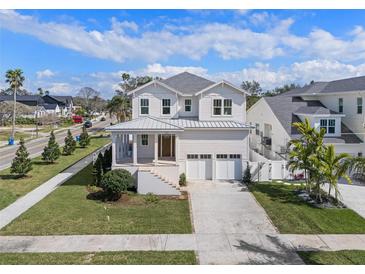 Charming two-story white home with a welcoming front porch, lush lawn, and a two-car garage at 323 Appian Ne Way, St Petersburg, FL 33704