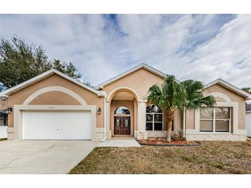 Tan house with palm tree, double doors, and a two-car garage at 1833 Hillcrest St, Tarpon Springs, FL 34689