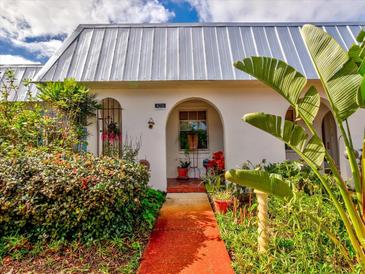 Charming bungalow with metal roof, lush landscaping, and a welcoming walkway at 4231 Tamargo Dr # 3, New Port Richey, FL 34652