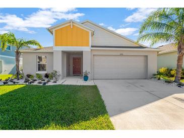 Two-story house with gray and yellow exterior, two-car garage, and landscaped lawn at 12931 Twin Bridges Dr, Riverview, FL 33579