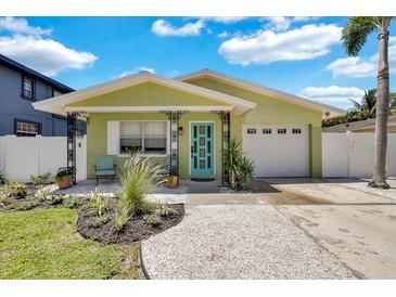 Charming light green house with a teal door, landscaped yard, and attached garage at 1742 Mississippi Ne Ave, St Petersburg, FL 33703