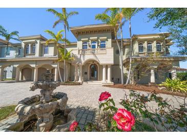 Stately two-story home featuring a grand entrance, fountain, lush landscaping and elegant architectural details at 26 Sunset Bay Drive, Belleair, FL 33756