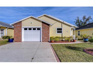 Cute yellow house with a brick accent and a two-car garage at 37347 Derbyshire Dr, Zephyrhills, FL 33542